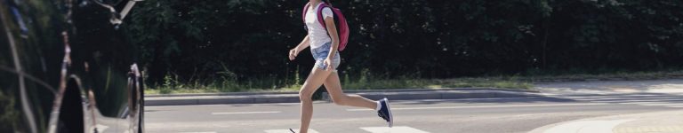 Panorama of car and girl running on pedestrian crossing to the school